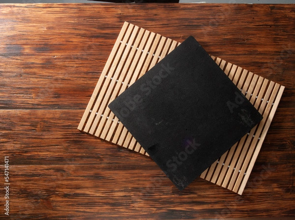 Fototapeta Tabla negra sobre mantel individual sobre mesa de madera. Black board on placemat on wooden table. 