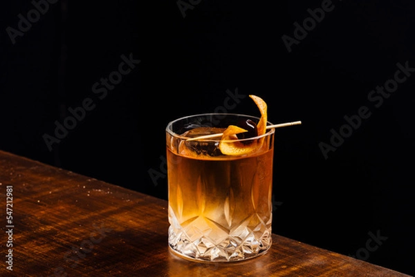 Fototapeta old fashioned cocktail on a wooden table and black background