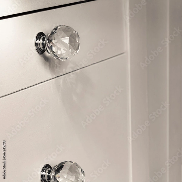 Fototapeta Close-up of acrylic drawer pulls with selective lighting over them. Part of a white bed table