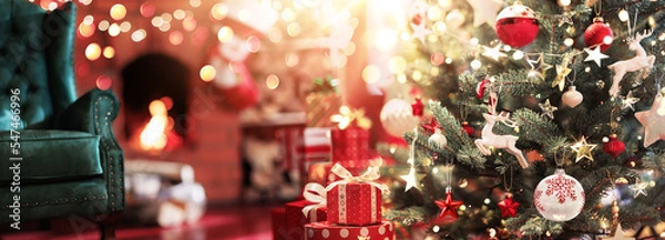 Fototapeta Christmas tree with toys and gifts on the background of a fireplace with fire. Magical room with the throne of Santa Claus
