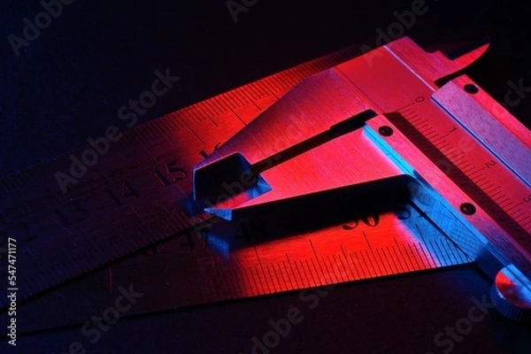 Fototapeta caliper and metal rulers illuminated in red and blue. close-up