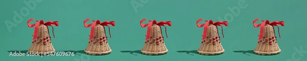 Obraz Festive natural décor Christmas idea with wooden bells and red ribbons on green background. Minimal New Year winter season concept.