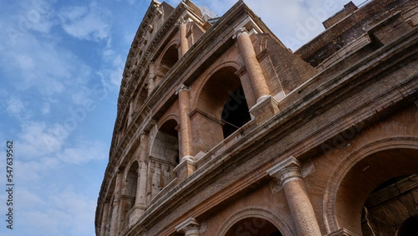 Fototapeta Colesseum on the white cloudy and blue sky background, from below or on the edge.