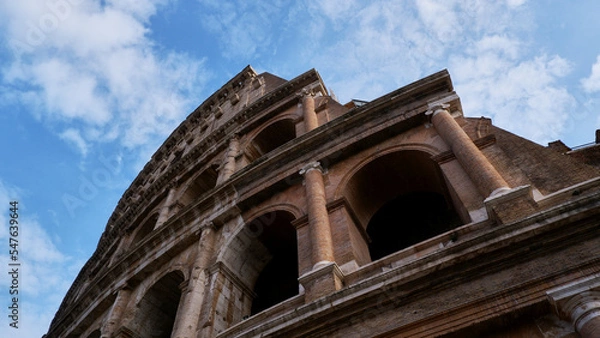 Fototapeta Colesseum on the white cloudy and blue or azure sky background, bottom view or from below.