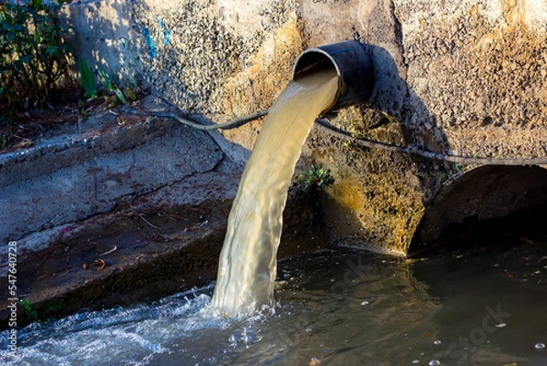 Fototapeta Wastewater sewage pipe dumps the dirty contaminated water into the river. Water pollution, environment contamination concept.