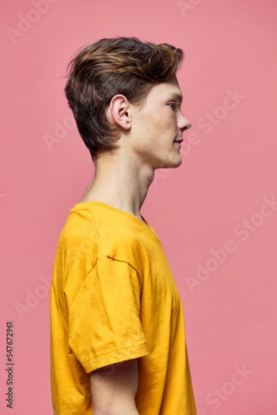 Fototapeta a man in a yellow tank top poses sideways to the camera on a pink background