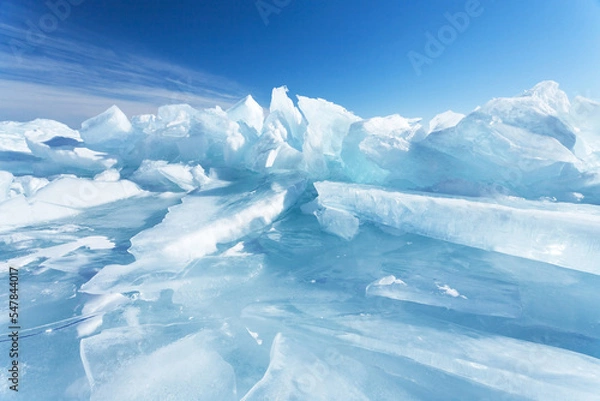 Fototapeta Winter natural background with fragments of blue ice and heaps of pieces of ice floes on Lake Baikal on a sunny frosty day. Abstract cold background, mock up. Harsh lifeless environment