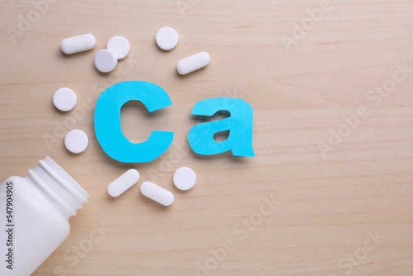 Obraz Paper symbol Ca (Calcium), medical bottle and pills on violet background, top view