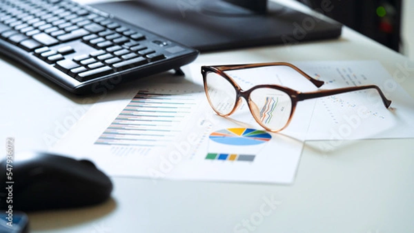Fototapeta Office workplace desk. Business reports with graphics. Financial spreadshets left on the desk after a tiring day's work. Work hard.