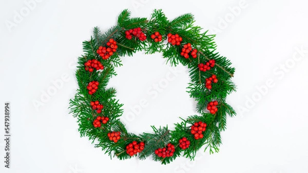 Fototapeta Natural branches of spruce and arborvitae are decorated with red rowan berries. Eco friendly Christmas wreath.