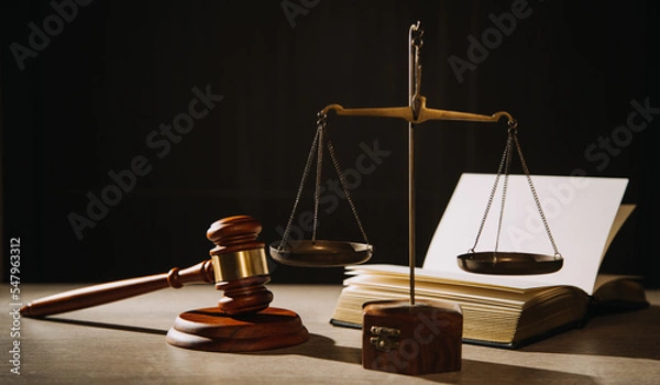 Fototapeta Justice and law concept.Male judge in a courtroom with the gavel, working with, computer and docking keyboard, eyeglasses, on table in morning light