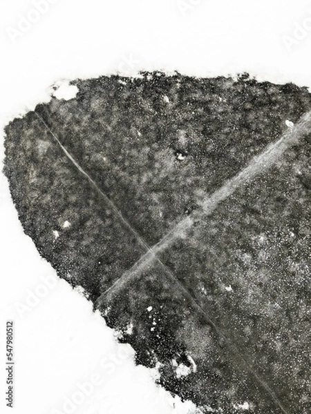 Fototapeta Close up of the ice covering a frozen lake with snow