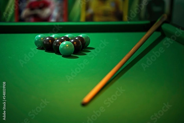Fototapeta green pool table with green and black cue and balls. low depth of focus. to use as background