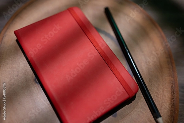 Fototapeta closed scatbook with pencil on wooden background. blind shade. for mockup or background