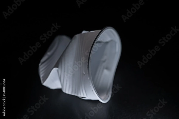 Fototapeta Crumpled disposable plastic cup. white cup on black background. to use in presentations or as a background