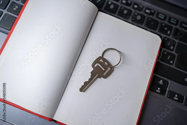 Fototapeta notebook and key over laptop. blank scatbook with house key over computer. for real estate presentations, purchase of own house. for presentation background