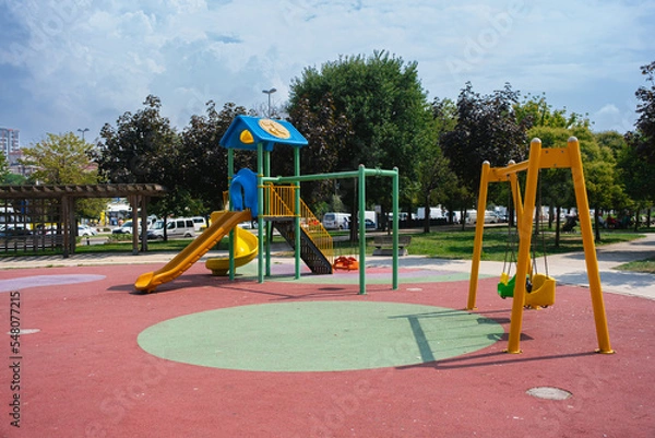 Fototapeta Children playground, swing in the park for children in public park. small empty colorful playground in the city
