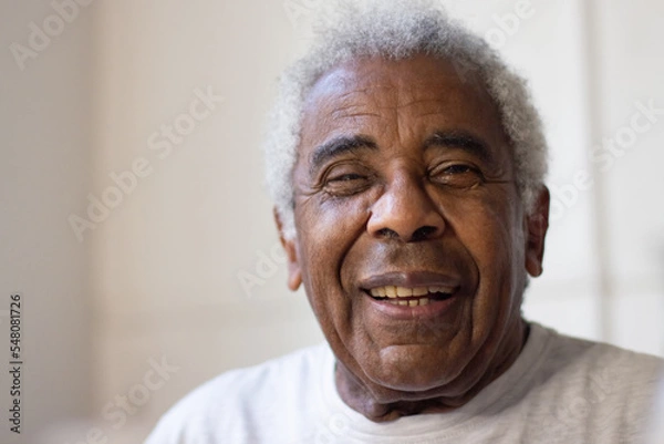 Fototapeta Close-up of elderly mans face. Happy African American man with grey and curly hair smiling and looking at camera with joy. Happy life and taking care of elderly people concept