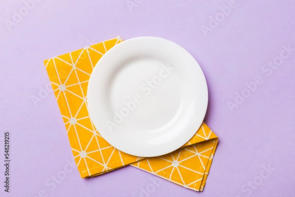 Obraz Top view on colored background empty round white plate on tablecloth for food. Empty dish on napkin with space for your design