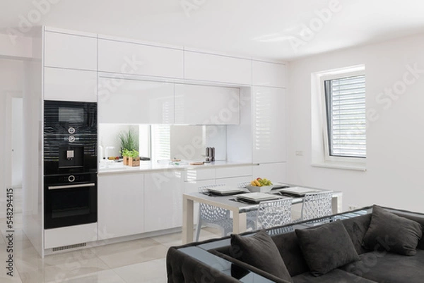 Fototapeta White kitchen with built in appliances in modern apartment