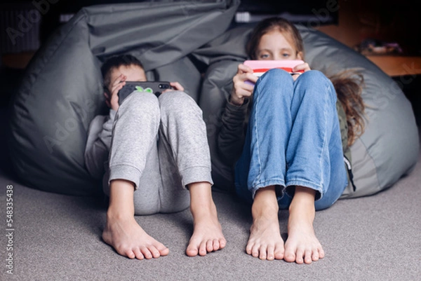 Fototapeta Children play video games. Children with a phone in their hands. Addiction to the phone