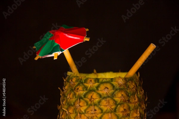 Fototapeta Exotic pineapple in the shape of a drink, with organic straw and mini umbrella