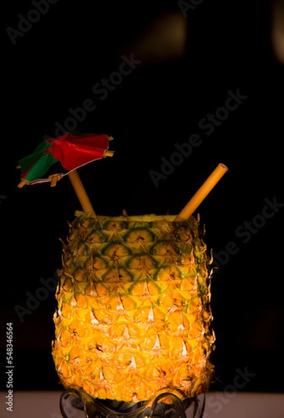 Fototapeta Exotic pineapple in the shape of a drink, with organic straw and mini umbrella