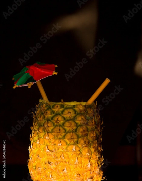 Fototapeta Exotic pineapple in the shape of a drink, with organic straw and mini umbrella
