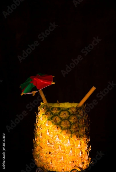 Fototapeta Exotic pineapple in the shape of a drink, with organic straw and mini umbrella