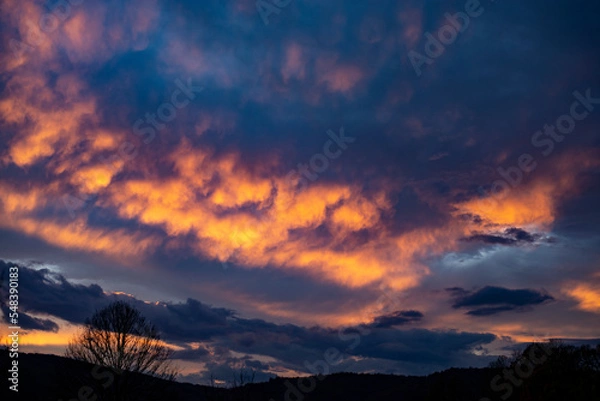 Fototapeta Beautiful Sunset in the Mountain with Orange and Blue Clouds.