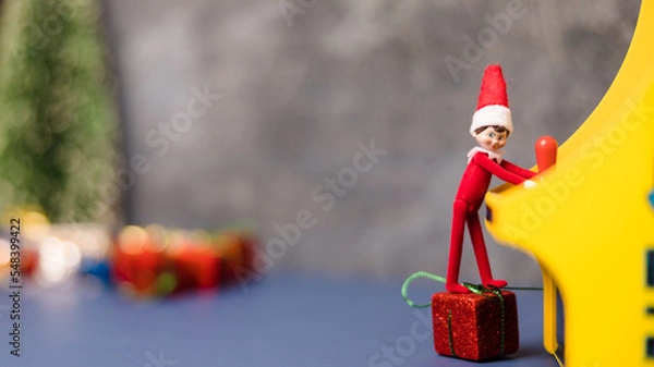 Fototapeta Elf standing on present playing video games.
