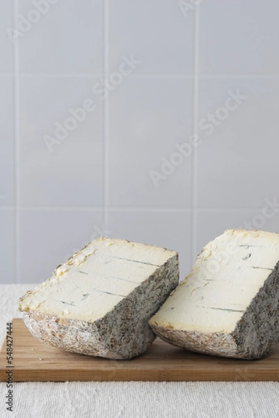 Obraz Two halves of round blue cheese wheel on wooden cutting board on light background, selective focus