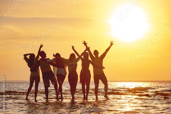 Obraz Group of happy young friends are having fun and embracing at sunset beach