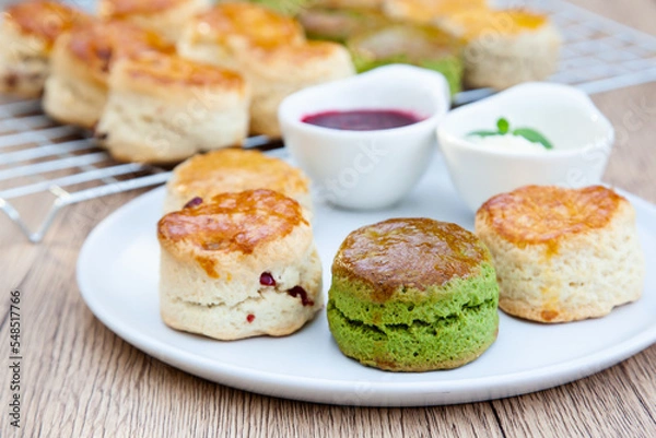 Fototapeta Four flavours of homemade scone with raspberry jam and clotted cream (butter, cranberry, matcha and Earl Grey)