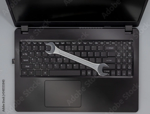 Obraz Stalowy klucz leżący na klawiaturze laptopa, naprawa komputera.