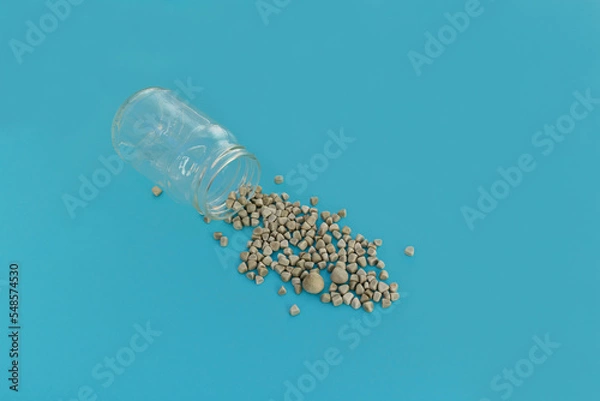 Obraz Gallstones next to specimen jar on blue background
