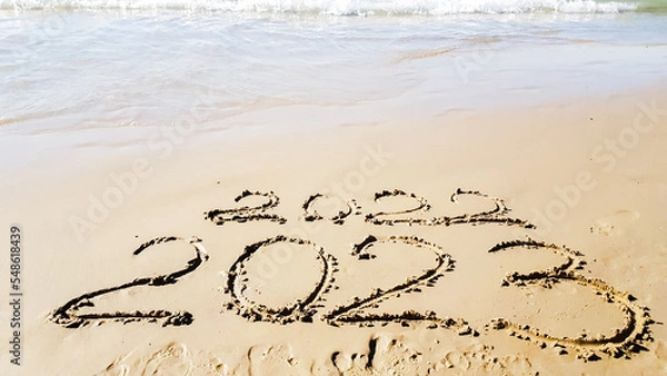 Obraz the inscription on the sand on the beach 2022 2023 is washed away by a wave. christmas at sea