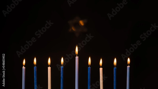 Fototapeta Menorah candles during Hanukkah with Star of David on a black background