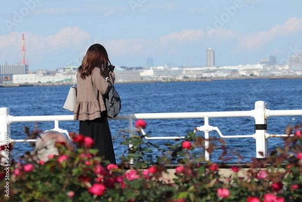 Obraz 海辺の公園でスマホをいじる若い女性