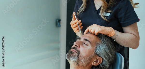 Obraz An Anonymous Female Beautician Giving Male Patient Botox Injection In A Forehead