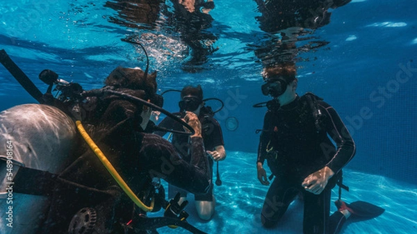 Fototapeta diving instructor teaches students to scuba dive in swimming pool. couple getting first experience with scuba diving under the guidance of experienced recreational diving instructor on vacation.