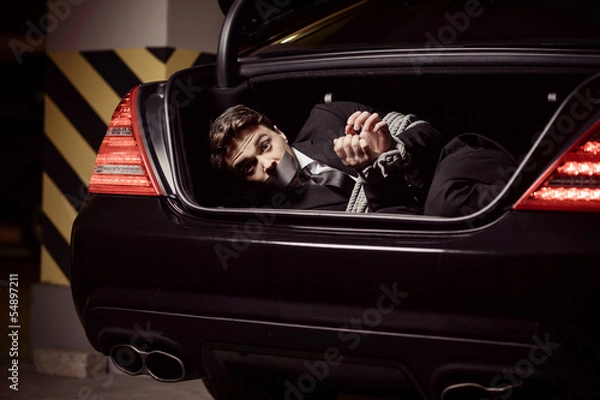 Obraz Kidnapped businessman. Tied up businessman lying in the car trun