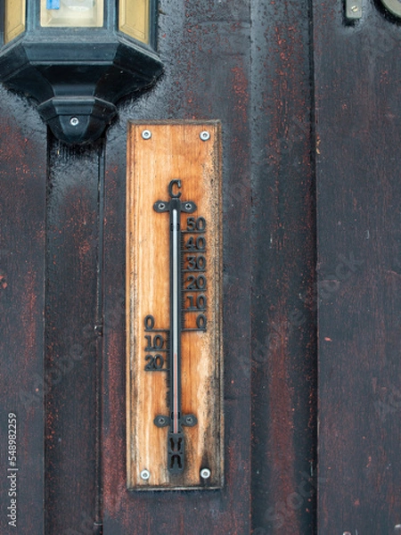 Fototapeta Old worn thermometer placed outside in the cold on old painted wodden facade