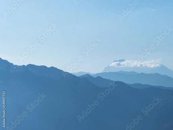 Obraz Light blue mountains in the distance, aerial perspective, mountain atmosphere. Beautiful mountain landscape, clouds over the peaks of the mountains,