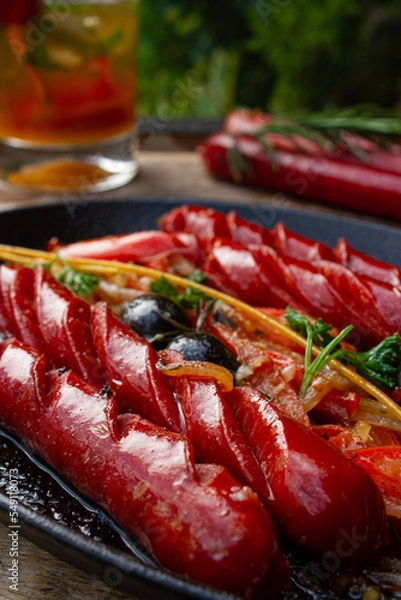 Obraz frying pan with sausages, black olives, rosemary. Outdoor with a beverage.