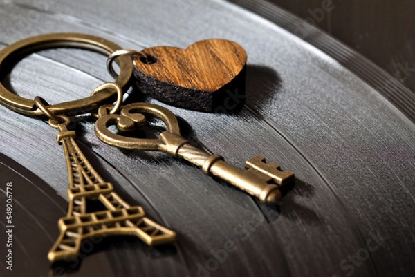 Fototapeta key with a keychain in the shape of a heart and an eiffel tower on a black background
