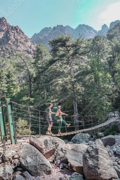 Fototapeta Couple crossing a suspension bridge.