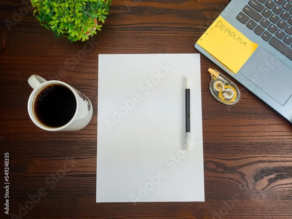 Fototapeta Flat lay, a mockup of a notebook. A workspace with white notebooks, laptops, office supplies, pencils, and coffee cups in the office background of a wooden desk from top view.