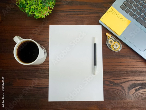 Fototapeta Flat lay, a mockup of a notebook. A workspace with white notebooks, laptops, office supplies, pencils, and coffee cups in the office background of a wooden desk from top view.