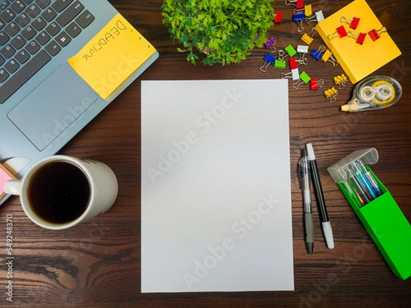 Obraz Flat lay, a mockup of a notebook. A workspace with white notebooks, laptops, office supplies, pencils, and coffee cups in the office background of a wooden desk from top view.